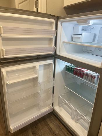 A white refrigerator with the door open and shelves inside.